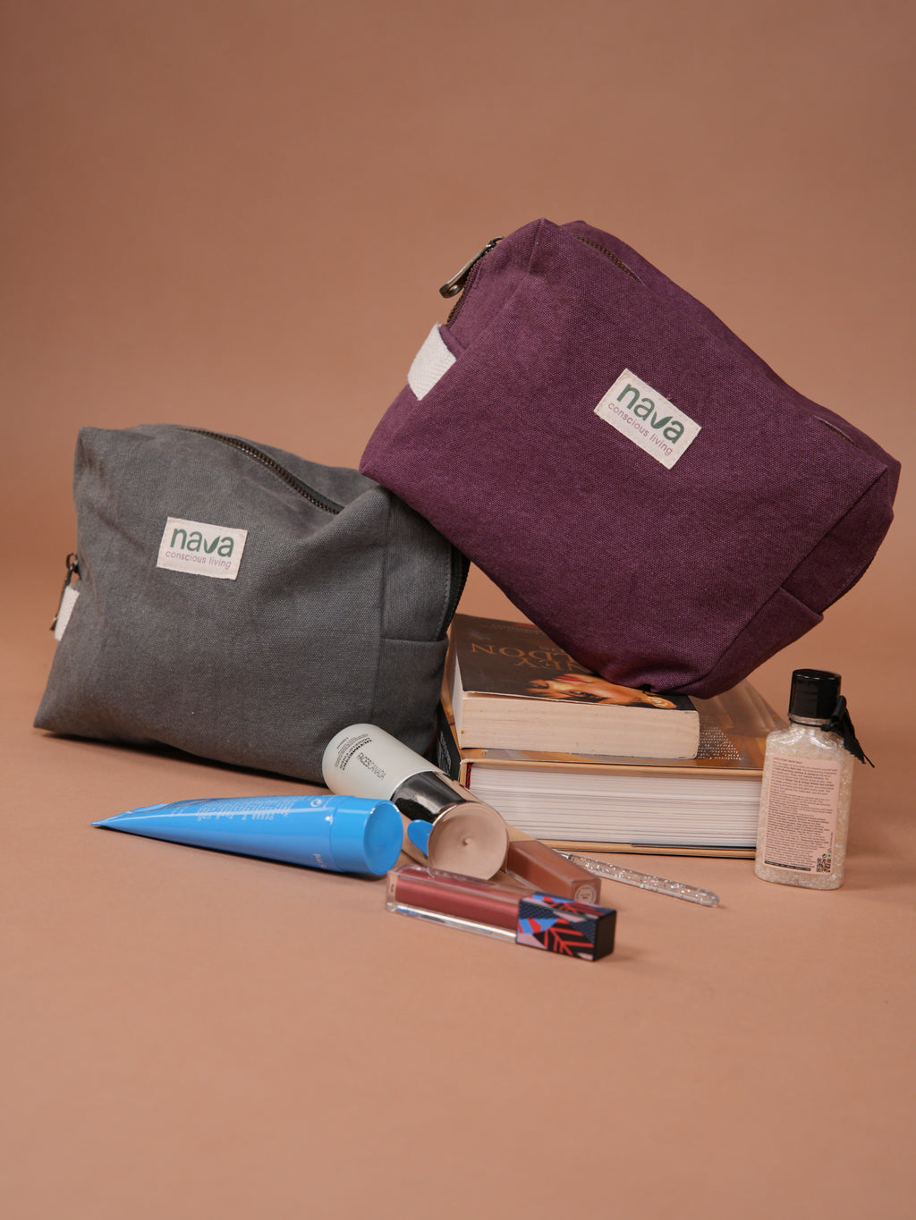 Two Nava Cotton pouches, one gray and one purple, with cosmetic items on a brown background.